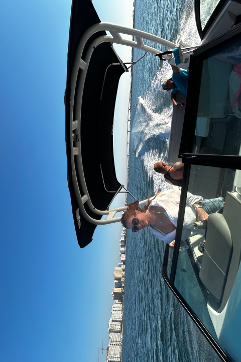 People standing on a speedboat with a city skyline in the background.